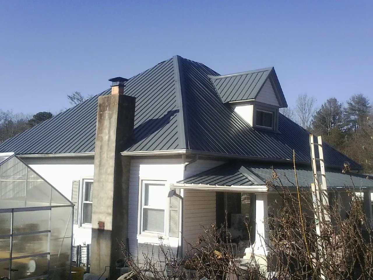 Dark blue standing seam metal roof on a white farmhouse with dormer — Slate & Tile Roof Repair by Roofing Brothers in Red Feather Lakes