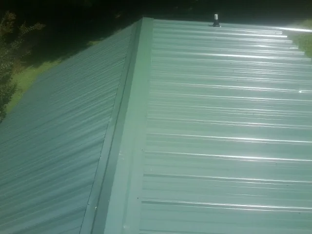 New green metal panels meeting at the ridge of a roof — Flat Roof Repair work by our crew in Red Feather Lakes