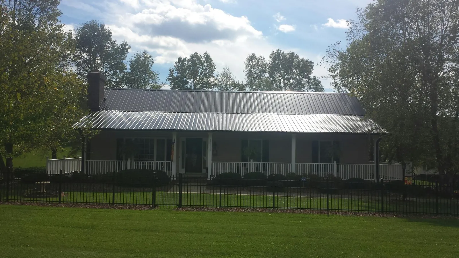 Gray metal roof on a brick ranch with a full width front porch — Gutter Guard Installation work by our crew in Red Feather Lakes
