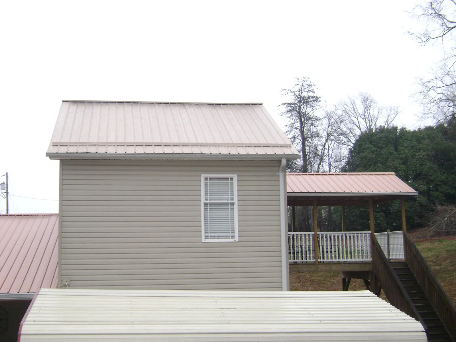 Tan metal roofs on a two story addition and attached porch, from a Roof Replacement job in Red Feather Lakes
