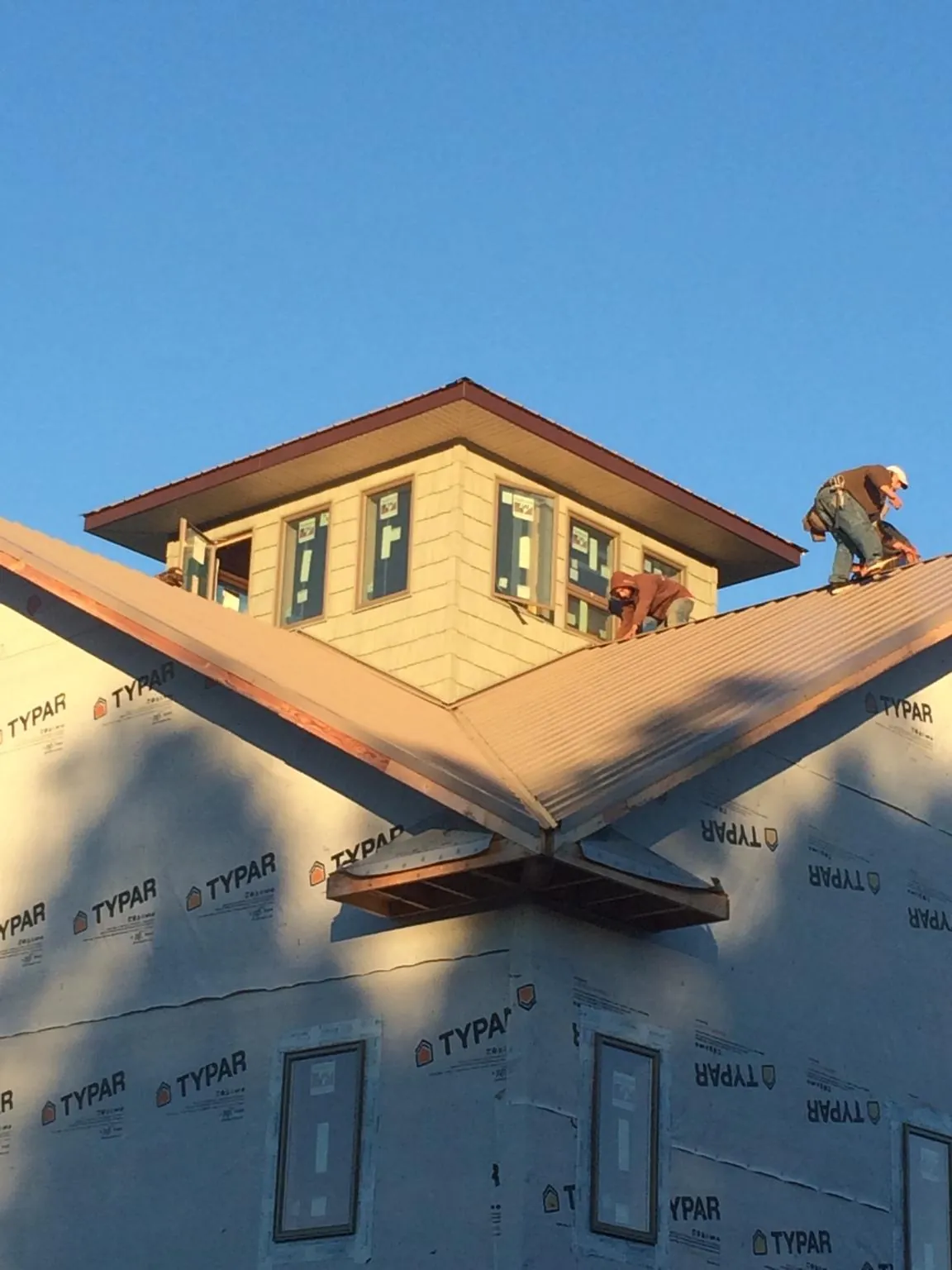 Roofers working around a rooftop cupola on a new metal roof at sunset — Roof Waterproofing in Red Feather Lakes by Roofing Brothers